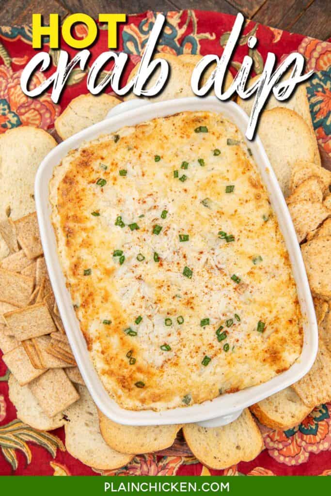 baking dish of crab dip surrounded by crackers and toasts on a table with text overlay