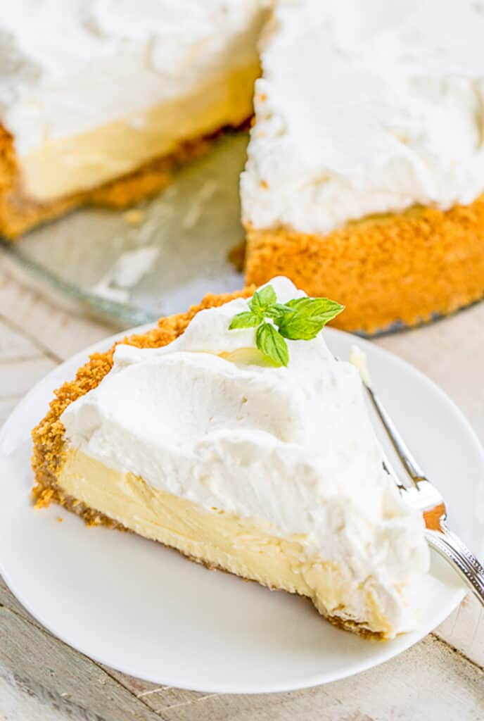 slice of lemon pie topped with whipped cream and mint on a plate