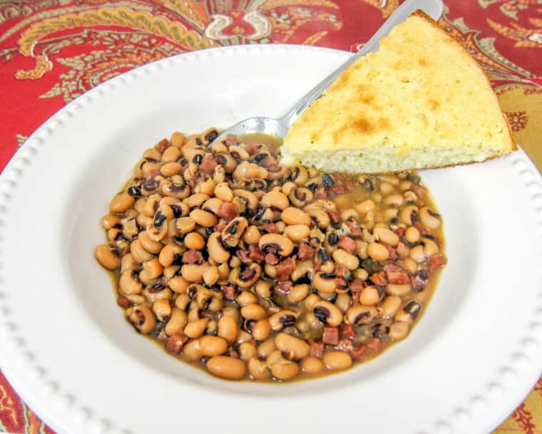 bowl of black eyed peas and ham with cornbread