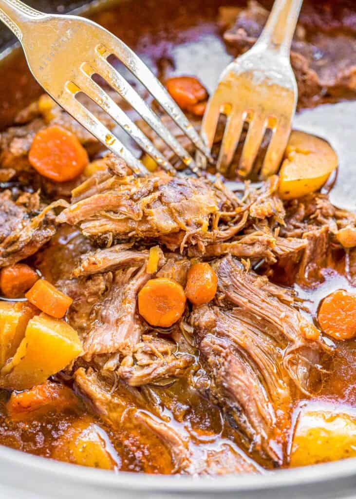 shredding pot roast with potatoes and carrots in a crockpot