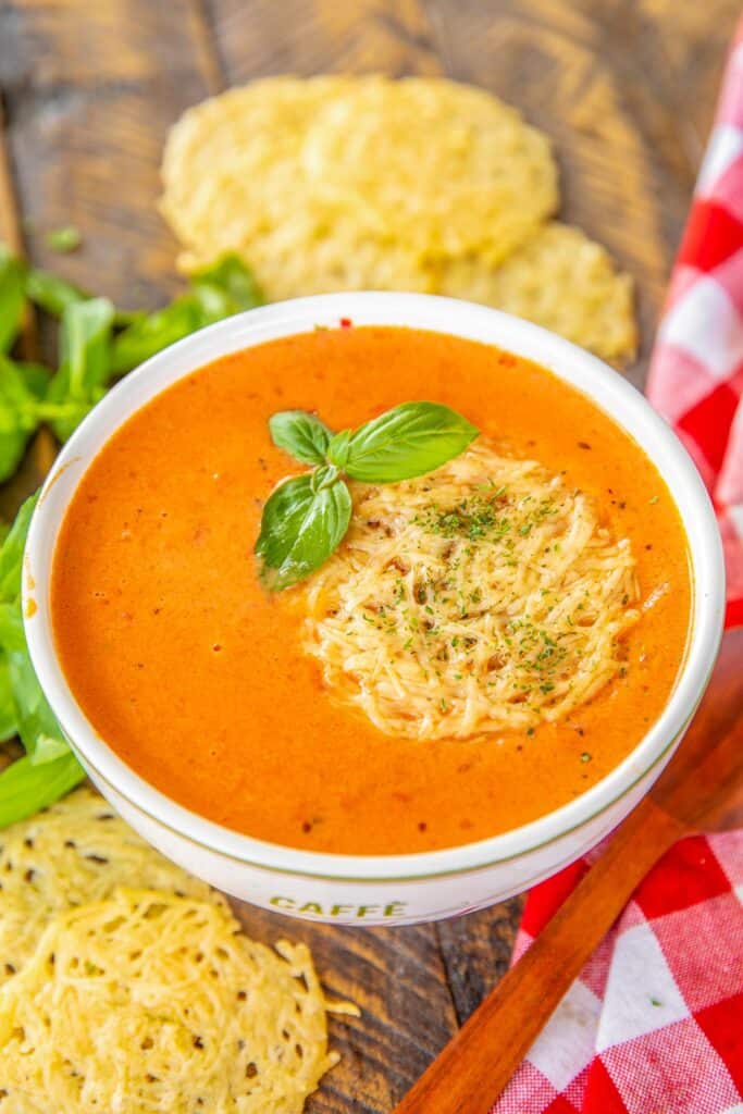 bowl of tomato soup topped with basil and parmesan cheese