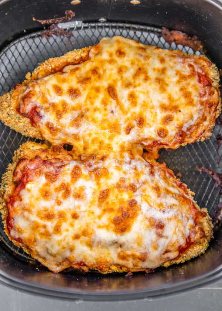 two pieces of chicken parmesan in air fryer basket