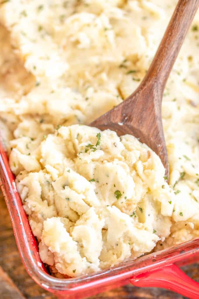 scooping mashed potatoes from baking dish
