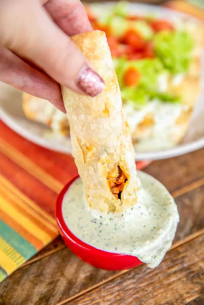 dipping taquito into dressing