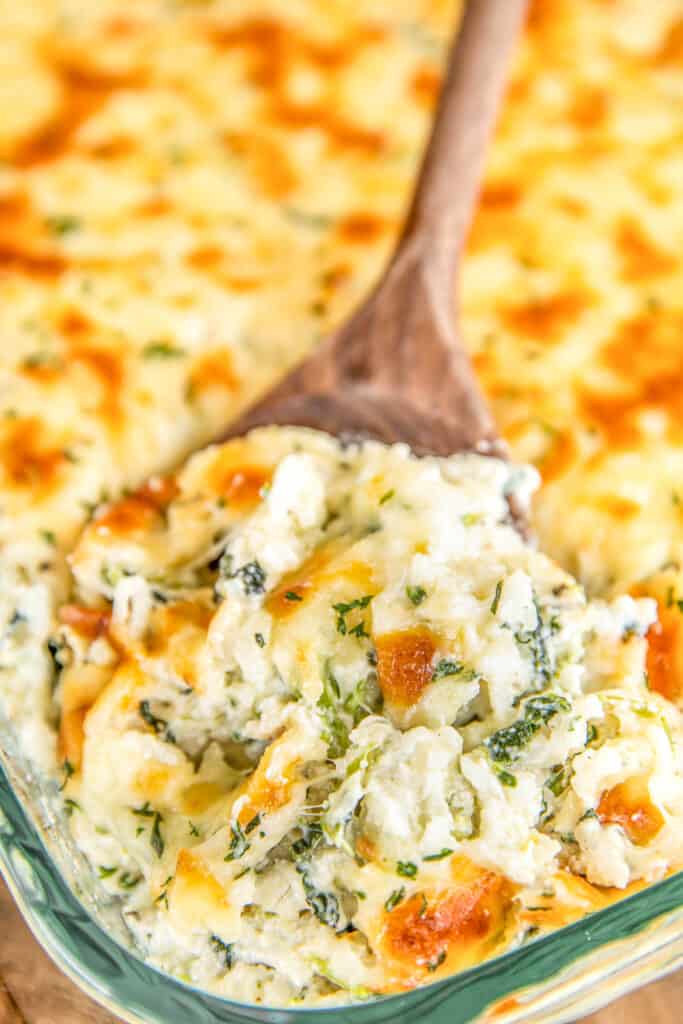 scooping spinach artichoke rice from baking dish