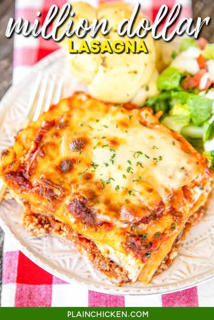 slice of million dollar lasagna on a plate with salad and a roll