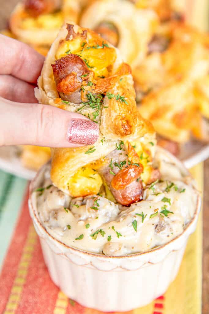 dipping sausage egg & cheese puff pastry breakfast sandwiches into gravy