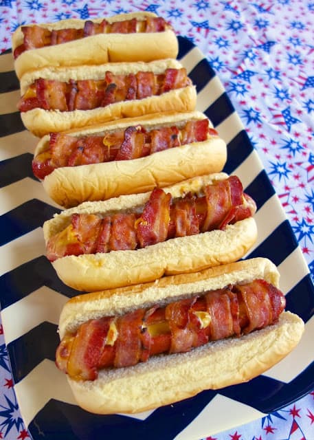 Cheesy Bacon Wrapped Hot Dogs - hot dogs stuffed with cheese and wrapped in bacon - bake for 10 minutes and you have the BEST hotdogs! Use precooked bacon to get good and crispy bacon. Can prep the hot dogs and bake the next day.