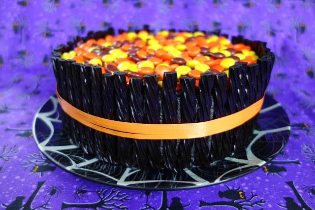 Spooktacular Halloween Cake - orange and black zebra cake surrounded with black licorice and topped with Reeses pieces. Use cake mix for a quick and festive Halloween treat!