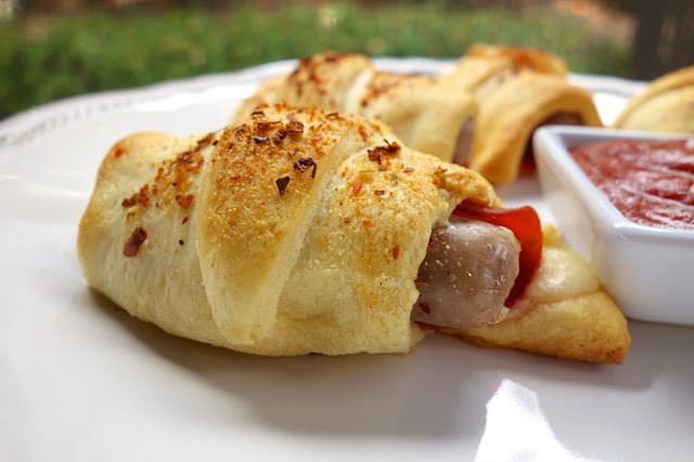 Sausage and Pepperoni Pizza Crescents - link sausage, pepperoni and mozzarella baked in crescent rolls. Serve with warm pizza sauce - SO good and SO quick and easy. Kids and adults gobble these up. Great for lunch, dinner or parties!!