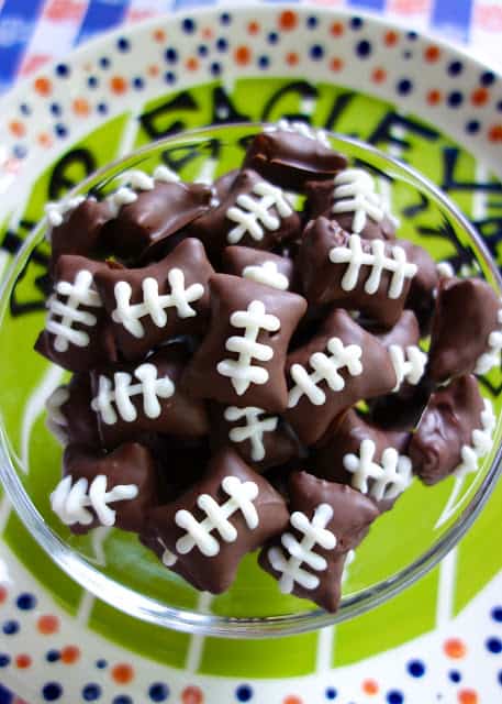 Chocolate Dipped Football Pretzel Bites - easy no-bake football party food! SO easy and SO adorable!!! Tastes like a butterfinger. Peanut Butter filled pretzels, chocolate candy coating, white candy melts and a squeeze bottle. A must for tailgating!