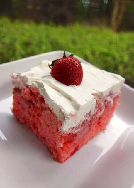Strawberries and Cream Poke Cake - strawberry cake soaked with strawberry ice cream topping and sweetened condensed milk then topped with strawberries and whipped cream. SO delicious! Great cake for a crowd. Gets better as it sits!