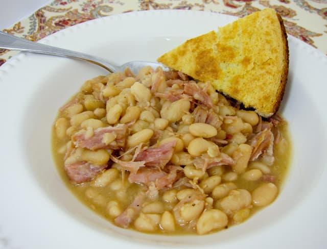 Slow Cooker Ham and White Beans - only 4 ingredients! This is a family favorite. Dry white beans, leftover ham, onions and water. We serve it with homemade cornbread for a hearty meal. Our favorite way to use up leftover holiday ham.