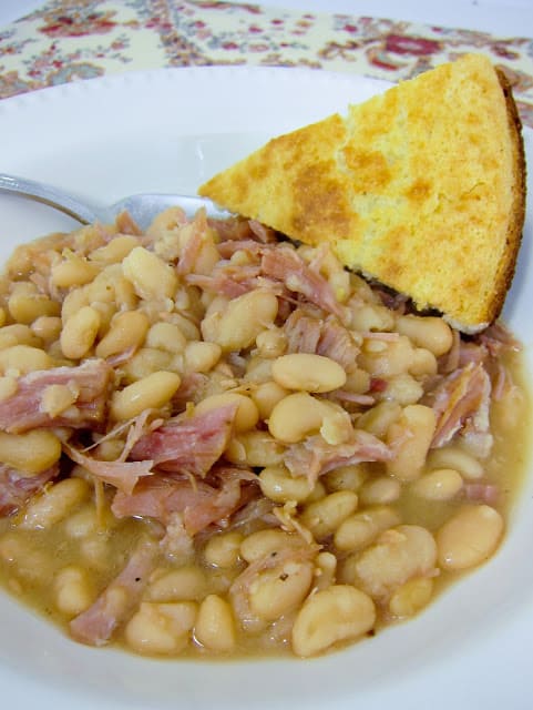 Slow Cooker Ham and White Beans - only 4 ingredients! This is a family favorite. Dry white beans, leftover ham, onions and water. We serve it with homemade cornbread for a hearty meal. Our favorite way to use up leftover holiday ham.