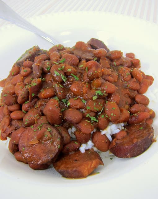 THE BEST Slow Cooker Red Beans & Rice - dried red beans, andouille sausage, water, tomato sauce, Worcestershire, onion, green pepper and cajun seasoning - serve over hot white rice. This is the best red beans and rice outside of New Orleans! SO easy and crazy delicious!