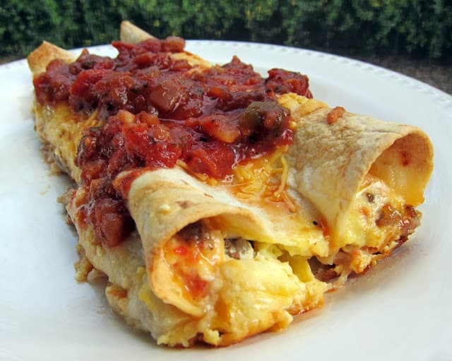 Southwestern Quichiladas Recipe - overnight breakfast enchiladas - tortillas stuffed with sausage, Rotel and cheese with an egg and half and half mixture poured over top - assemble the night before and pop in the oven for an easy breakfast! Top with salsa to kick it up a notch. Great for overnight guest or school morning breakfast.