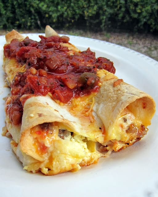 Southwestern Quichiladas Recipe - overnight breakfast enchiladas - tortillas stuffed with sausage, Rotel and cheese with an egg and half and half mixture poured over top - assemble the night before and pop in the oven for an easy breakfast! Top with salsa to kick it up a notch. Great for overnight guest or school morning breakfast.