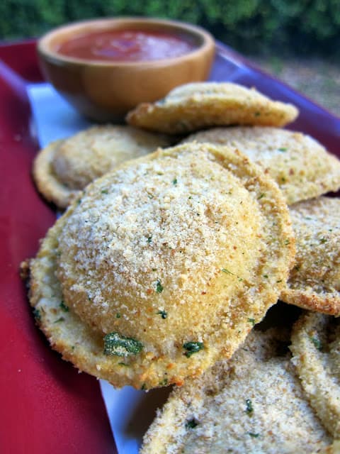 Oven Toasted Ravioli - baked not fried! SO easy and ready in about 15 minutes. Great for parties! Frozen ravioli, coated in parmesan cheese and baked. Dip in warm marinara or pesto.