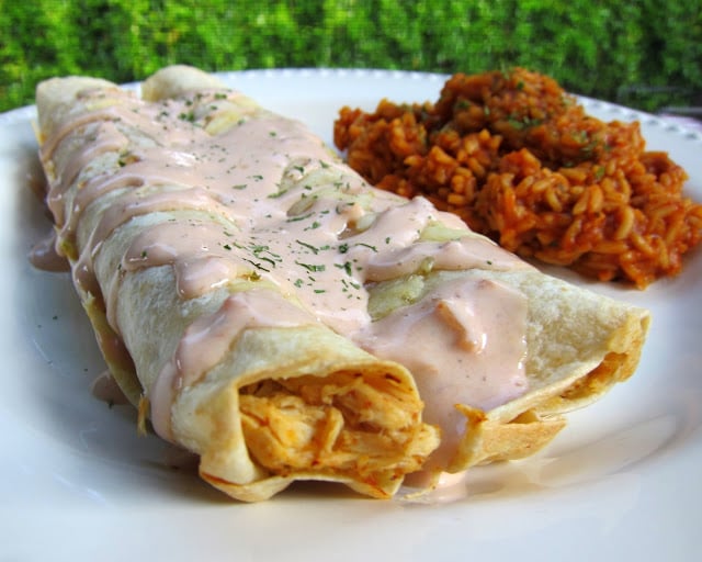 Chicken Ranch Enchiladas and Rice {Slow Cooker} Recipe - chicken slow cooked in taco seasoning, ranch mix, chicken broth. Top tortillas with cooked chicken, cheese, salsa and Ranch and bake for 20 minutes. Use leftover juices in crockpot to make super flavorful rice to go with the enchiladas! SO good. Better than the Mexican restaurant!