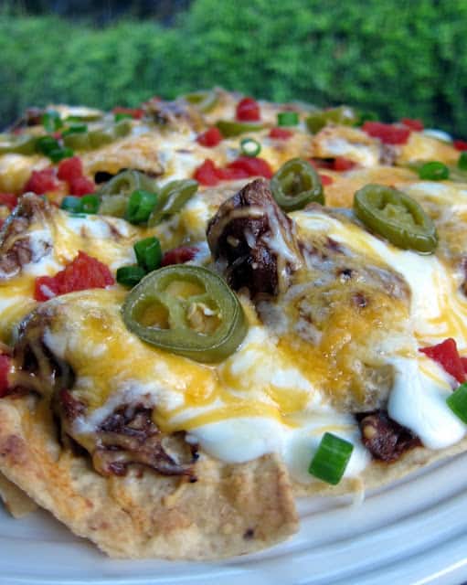 Pot Roast Nachos Recipe - use leftover pot roast to make amazing baked nachos! Pot roast, bbq sauce, chipotles, tortilla chips, cheese, sour cream, jalapeños, tomatoes and green onions. Copycat recipe from Ditka's in Chicago.