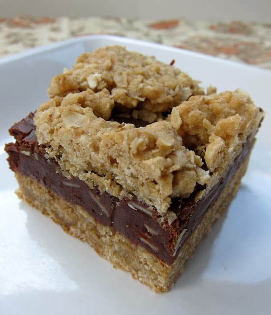 Oatmeal Fudge Bars - oatmeal almond cookie bars with a yummy fudge layer in the middle. Oatmeal, flour, baking soda, salt, butter, brown sugar, eggs, vanilla, sweetened condensed milk, chocolate chips and almonds. Great make ahead dessert. Perfect potluck dessert.