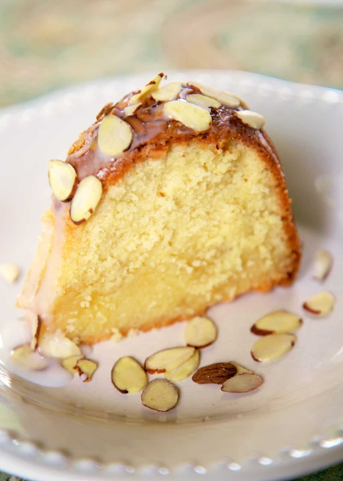 Amaretto Pound Cake - dangerously delicious!!! LOADED with tons of great almond flavor. Moist homemade cake topped with a homemade almond syrup and almond glaze. I ate WAY too much of this yummy cake!! Butter, cream cheese, sugar, amaretto, almond extract, flour, eggs, sliced almonds, powdered sugar and milk. #poundcake #dessert #dessertrecipe