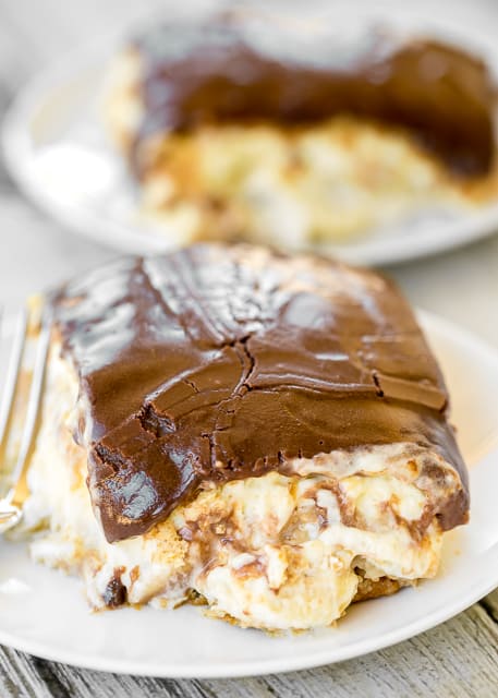 Banana Pudding Eclair Cake - I am in LOVE with this easy no-bake dessert. Great for potlucks, cookouts and Easter! Graham crackers, vanilla pudding, banana pudding, cool whip, bananas, chocolate frosting. Can make ahead and refrigerate before serving. Everyone RAVES about this yummy dessert recipe!! 