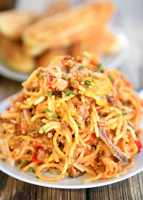 Chili Spaghetti Casserole - comfort food at its best! Spaghetti, hamburger, onions, garlic, chili, tomatoes, sour cream, shredded cheese and French fried onions. CRAZY good!!! Ready to eat in under an hour. Great for a potluck and tailgating! Can freezer or later.