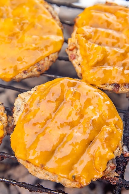 chicken burger patties topped with cheese on the grill