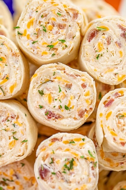 Crack Chicken Pinwheels - I am OBSESSED with these sandwiches! Cream cheese, cheddar, bacon, ranch and chicken wrapped in a tortilla. So simple to make with rotisserie chicken and precooked bacon. Can make ahead of time and refrigerate until ready to eat. Perfect for parties and tailgating!! #pinwheels #chicken #tailgating #bacon #sandwich #partyfood