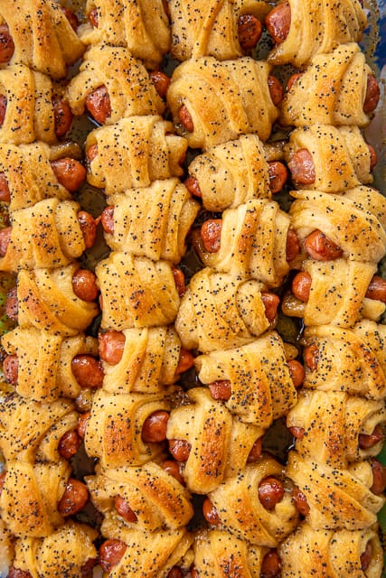 Glazed Pigs in a Blanket - pigs in a blanket baked in a sweet and savory brown sugar glaze. Took these to a party and they were gone in minutes!!! Crescent rolls, dijon mustard, little smokies, brown sugar, butter, poppy seeds and Worcestershire sauce. I have zero self-control around these things! Dangerously delicious!! A MUST for all your tailgates and parties! #tailgating #Pigsinablanket #partyfood #appetizer