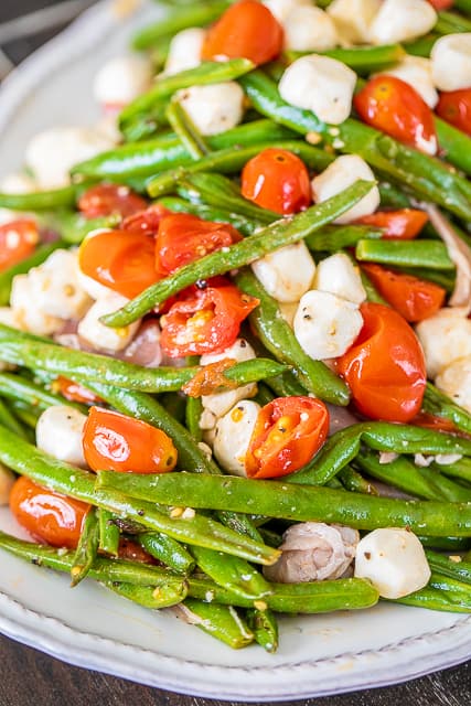 Italian Green Bean Salad - quick and delicious side dish! Green beans, tomatoes, garlic, olive oil, prosciutto, and mozzarella tossed in lemon juice and olive oil. Can serve hot or cold. Great for potlucks and cookouts. Can make in advance and refrigerate until ready to serve. Everyone always asks for the recipe! YUM! #salad #greenbeans #vegetable