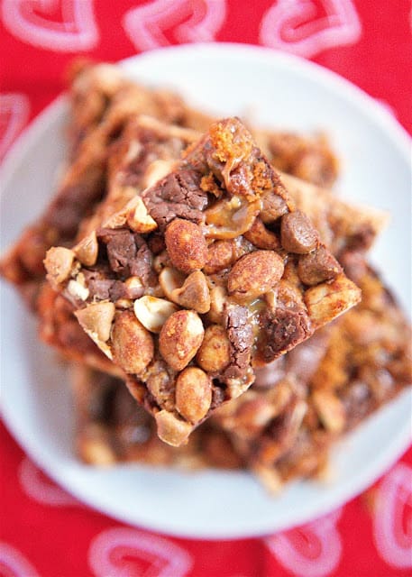 Peanut Butter Snickers Magic Bars - snickers baking bites, peanut butter chips, honey roasted peanuts on top of a graham cracker crust and drowned in sweetened condensed milk. SO easy to make and SOOO delicious! Everyone raved about them!