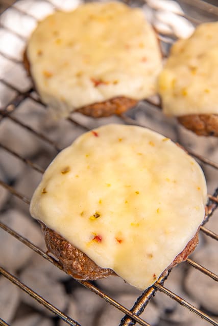 Pepper Jack Whiskey Burgers - seriously delicious! Ground beef, garlic salt, Worcestershire sauce, chili powder and a shot of whiskey. Top with sliced pepper jack cheese. Made these at our cookout and everyone asked for the recipe! Can make ahead of time and freeze patties for later. YUM! #grill #burgers #tailgating #freezermeal #beef