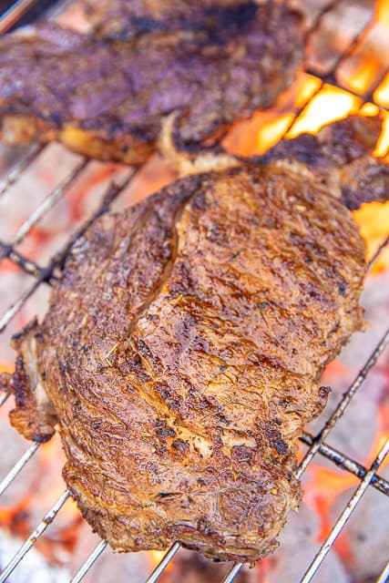 ribeye steaks being cooked on the grill