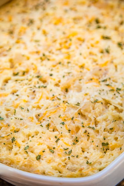 Cheesy Potato Casserole - dangerously delicious!!!! Loaded with three different types of cheeses - cheddar, parmesan and swiss. Can make ahead and freeze for later!! Hash browns, sour cream, Cream of Potato soup, garlic, pepper, cheddar, parmesan and swiss. Great for parties and potlucks. The most requested potato casserole in our house! #casserole #potatoes #freezermeal #sidedish #cheese