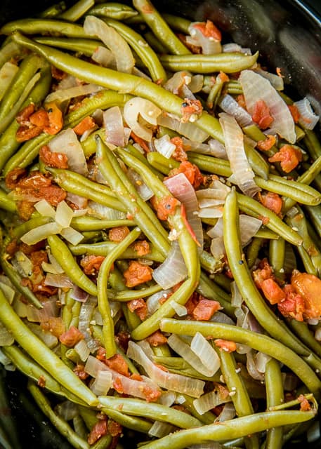 Slow Cooker Southern Green Beans - so simple and they taste AMAZING!! Just dump everything in the slow cooker and let it work its magic! Fresh green beans, red onion, lemon, tomatoes, garlic, chicken broth, salt and pepper. We make a batch on Sunday and eat the green beans all week with lunch and dinner. Great for cookouts, potlucks, tailgating and the holidays!