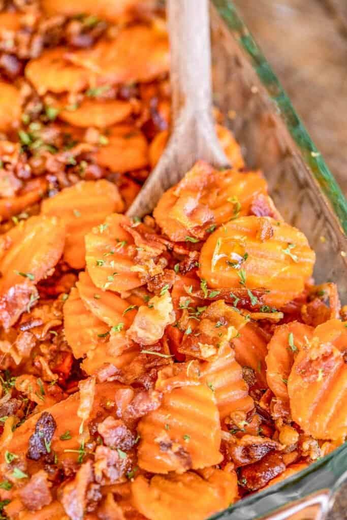 scooping bacon covered carrots from baking dish