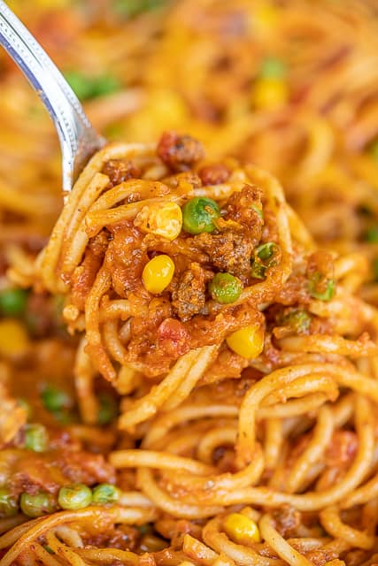 baked spaghetti with corn and peas on a fork