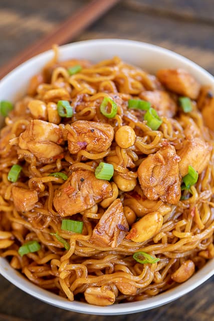 Spicy Sriracha Chicken Noodles - ready to eat in 15 minutes! No joke!!! SO easy!!! Only 6 ingredients - Chicken, ramen noodles, brown sugar, soy sauce, sriracha, and peanuts. Garnish with green onions. Great way to use up leftover chicken! Can add broccoli, green beans or asparagus. We ate this twice in one week. Everyone LOVES this easy noodle bowl!