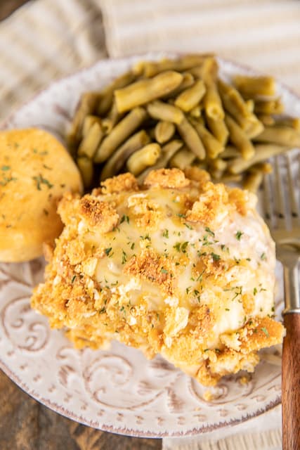 cheesy pork chops on a plate with green beans