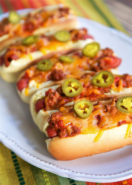 Taco Chili Dogs - hot dogs topped with a quick homemade taco chili and cheddar cheese. Hamburger, taco seasoning, tomato sauce, water and Rotel tomatoes. SO good! Can make chili ahead of time and reheat when ready to make the Taco Chili Dogs. These were a huge hit in our house!