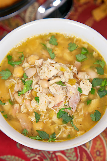 Slow Cooker White Chicken Chili recipe - chicken, seasonings, cannellini beans, chickpeas, green chilies - top with cilantro, cheese, sour cream and Fritos! SO good! Just dump everything in the slow cooker and forget it. Complete the meal with some cornbread. Quick and easy weeknight meal!
