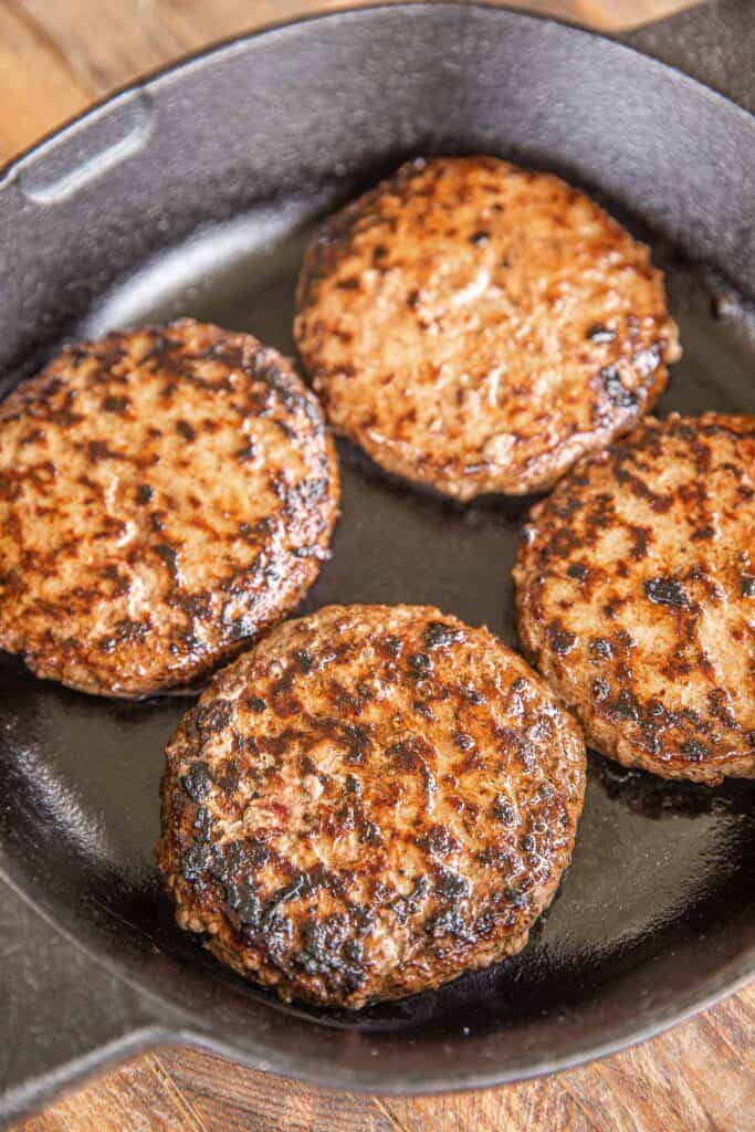 burgers cooking in a cast iron skillet