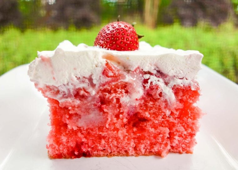 Strawberries and Cream Poke Cake - strawberry cake soaked with strawberry ice cream topping and sweetened condensed milk then topped with strawberries and whipped cream. SO delicious! Great cake for a crowd. Gets better as it sits!