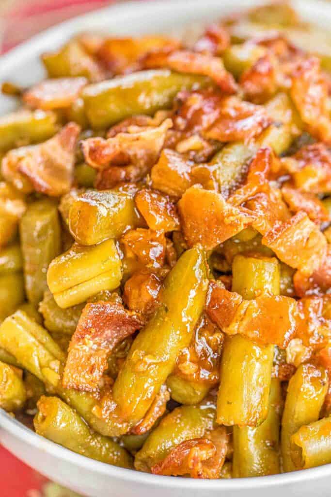 BBQ Smothered Green Beans - canned green beans baked in bacon, and a homemade BBQ sauce. This is the most requested green bean recipe in our house.Everybody gets seconds. SO good!! Great for a potluck. Everyone asks for the recipe! Super easy to make.