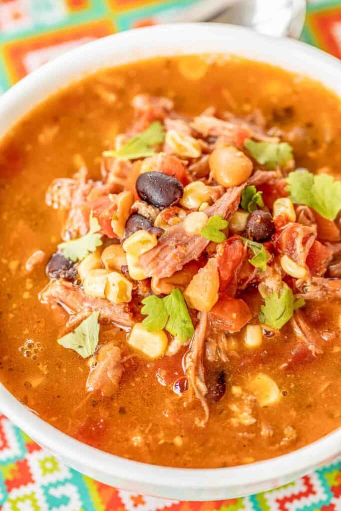 Pulled Pork Taco Soup - the BEST taco soup EVER!!! Pulled pork, pinto beans, black beans, diced tomatoes and green chiles, corn, taco seasoning, ranch seasoning, chicken broth. SO easy to make. Just dump everything in the pot, bring to a boil and simmer. Can also make in the #slowcooker. Great for tailgating and potlucks. Can freeze leftovers for a quick meal later. Our favorite taco soup recipe! #soup #taco #pulledpork