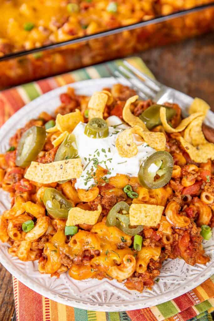 plate of chili mac with cheese, fritos, sour cream and jalapeños