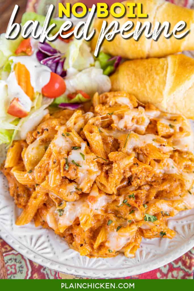 plate of baked penne pasta casserole with salad and bread