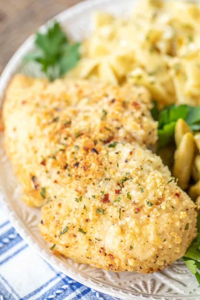 parmesan baked chicken on a plate with pasta and green beans